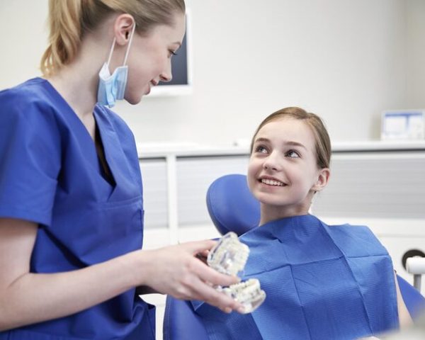 people-medicine-stomatology-health-care-concept-happy-female-dentist-showing-jaw-model-patient-girl-dental-clinic-office_380164-148925